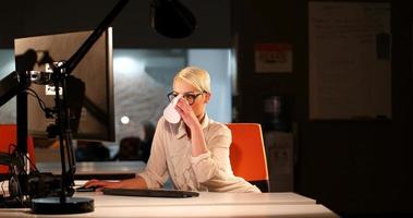 Frau, die im dunklen Büro am Computer arbeitet foto