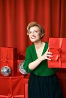 Reife stilvolle elegante Frau mit Geschenkbox auf rotem Hintergrund. party, mode, feier, anti-age-konzept. foto
