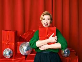 Reife stilvolle elegante Frau mit Geschenkbox auf rotem Hintergrund. party, mode, feier, anti-age-konzept.