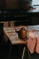 Vertikaler Stahlkessel auf Holztisch im gemütlichen Zimmer. alte antike Teekanne aus Aluminium, um Tee zuzubereiten. Vintage Haushaltswaren. foto