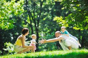 glückliches junges Paar mit ihren Kindern haben Spaß im Park foto