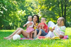 glückliches junges Paar mit ihren Kindern haben Spaß im Park foto