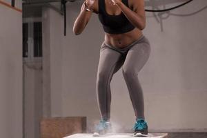 Schwarze Frau führt Boxsprünge im Fitnessstudio durch foto