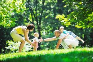 glückliches junges Paar mit ihren Kindern haben Spaß im Park foto