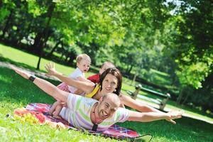 glückliches junges Paar mit ihren Kindern haben Spaß im Park foto