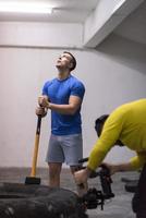 Männertraining mit Hammer und Traktorreifen foto