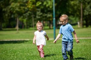 Jungen und Mädchen haben Spaß und laufen im Park foto