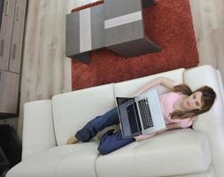 Frau entspannt und arbeitet zu Hause am Laptop foto