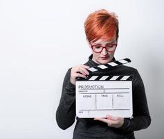 Rothaarige Frau mit Filmklöppel auf weißem Hintergrund foto