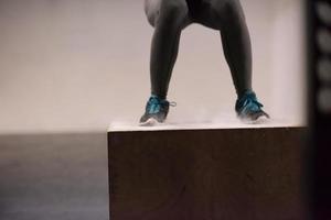 Schwarze Frau führt Boxsprünge im Fitnessstudio durch foto