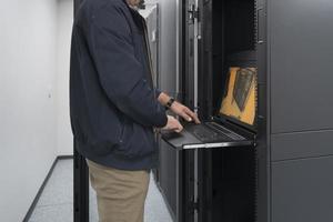 Nahaufnahme der Hände eines Rechenzentrumsingenieurs mit Tastatur auf einer spezialisierten Einrichtung eines Supercomputer-Serverraums mit männlichem Systemadministrator, der mit einem Datenschutznetzwerk für Cybersicherheit arbeitet. foto