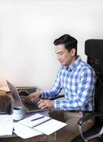 Mann, der von zu Hause aus mit einem Laptop am Schreibtisch arbeitet foto