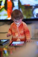 Baby spielt zu Hause mit Tablet foto