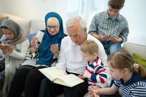 moderne muslimische großeltern mit enkelkindern, die den koran lesen foto