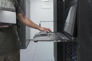 Nahaufnahme der Hände eines Rechenzentrumsingenieurs mit Tastatur auf einer spezialisierten Einrichtung eines Supercomputer-Serverraums mit männlichem Systemadministrator, der mit einem Datenschutznetzwerk für Cybersicherheit arbeitet. foto