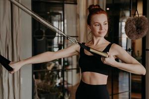 trainingszeit einer gesunden, glücklichen rothaarigen frau, die auf cadillac reformer trainiert foto