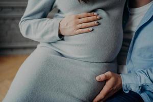 schwangere frau und ihr ehemann warten darauf, dass das baby glückliche eltern wird. schwangerschaft liebe familienbeziehung konzept. beschnittenes Bild foto