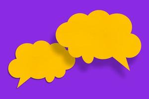 Sprechblasenförmige gelbe Papierwolke vor violettem Hintergrund. foto