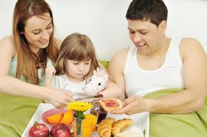 Glückliche junge Familie frühstückt im Bett foto