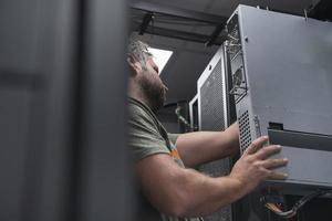 it-ingenieur, der im serverraum oder rechenzentrum arbeitet, stellt der techniker einen neuen server eines großrechner-supercomputers oder einer kryptowährungs-mining-farm in ein rack. foto