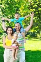 glückliches junges Paar mit ihren Kindern haben Spaß im Park foto