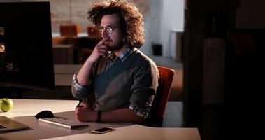 Mann, der im dunklen Büro am Computer arbeitet foto