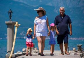 Großeltern und Enkelinnen, die am Meer spazieren gehen foto