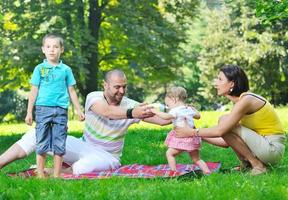 glückliches junges Paar mit ihren Kindern haben Spaß im Park foto