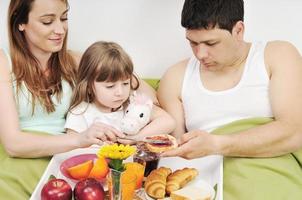 Glückliche junge Familie frühstückt im Bett foto