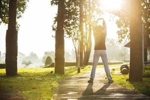 asiatische frau, die im park mit bewölktem himmel und linseneffekt joggt foto