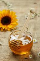 Honig in der Glasschüssel mit Sonnenblume auf dem hölzernen Hintergrund. foto