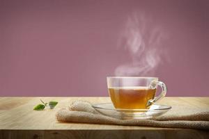 Tasse Tee mit Sackleinen auf dem Holztisch und rosa Hintergrund foto