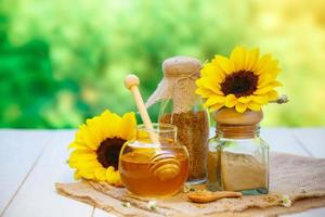 Glasschalen mit Honig, andere mit Pollen und Propolis. honigschöpflöffel, löffel, bienenwachs, sonnenblume auf dem holz foto