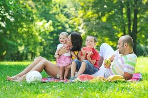 glückliches junges Paar mit ihren Kindern haben Spaß im Park foto