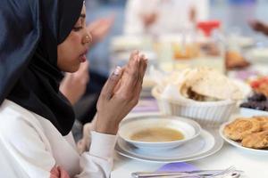 moderne schwarze muslimische frau, die vor dem iftar-abendessen betet foto