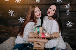 Zwei schöne Mädchen bieten der Kamera Geschenke an