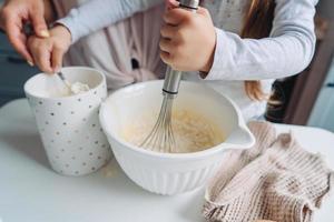 mama bringt ihrer kleinen tochter bei, essen zu kochen foto