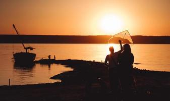 Ein junges Paar am Ufer lässt einen Drachen steigen foto