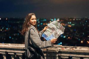 Mädchen mit einer Karte auf dem Hintergrund der Nachtstadt foto