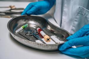 Krankenschwester in Gummihandschuhen, die ein Tablett mit chirurgischen medizinischen Geräten hält foto