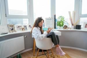 junge Frau auf Stuhl am Fenster foto