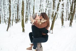 kerl hält das mädchen im schneepark an den händen foto