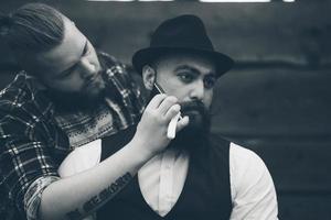 Friseur rasiert einen bärtigen Mann in Vintage-Atmosphäre foto