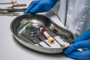 Krankenschwester in Gummihandschuhen, die ein Tablett mit chirurgischen medizinischen Geräten hält foto