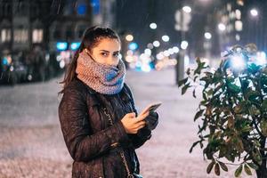 stilvolle frau, die telefon in der stadtstraße hält foto