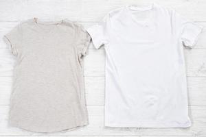 Weißes Nahaufnahme-T-Shirt mock-up flach lag auf weißem Holzhintergrund. Hemden für Männer und Frauen. draufsicht und kopierraum. modell sommer t-shirt und sommerzeit. Vorlage leeres Shirt. foto