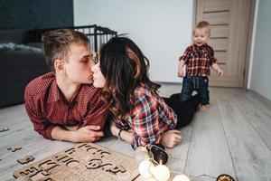 Mama küsst Papa auf dem Boden im Kinderzimmer foto