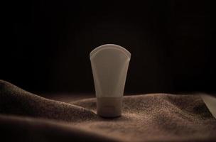 lotion tube modell isoliert auf braunem stoffhintergrund. foto