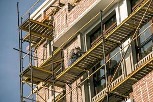 Hochhausausbauarbeiten. Ein Mitarbeiter streicht die Fassade eines Gebäudes foto