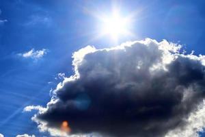 schöne aussicht auf sonnenstrahlen mit einigen linseneffekten und wolken am blauen himmel foto